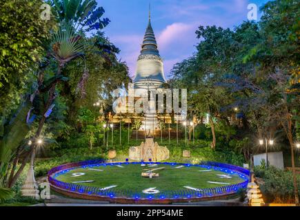 Nei giardini di Wat Penh, un regalo dalla Cina, coperto di erba verde, un grande orologio di lavoro, sotto la pagoda in cima alla collina di Wat Phnom, un importante punto di riferimento della città, n Foto Stock