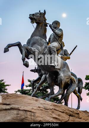 Posto su una grande roccia, luna al crepuscolo, lungo Riverside Walk.scultura in bronzo a grandezza naturale di due cavalli, uno che si alza in modo infedele, montato da eroico, hist Foto Stock