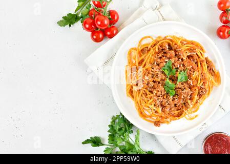 Spaghetti italiani bolognesi su piastra su sfondo bianco di pietra con spazio libero di testo. Vista dall'alto, piatto Foto Stock