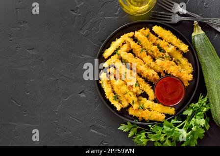 Le zucchine fritte si attaccano al piatto su fondo di pietra nera. Vista dall'alto, disposizione piatta Foto Stock