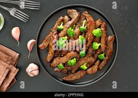 Il manzo e i broccoli si friggano su fondo nero. Vista dall'alto, disposizione piatta Foto Stock