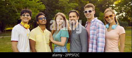Giovani amici felici uomini e donne in posa con sorriso per il ritratto di gruppo nel parco verde estivo Foto Stock