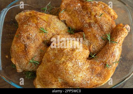 Collant di pollo marinato con sale, pepe nero, rosmarino e paprika pronti per essere cotti Foto Stock