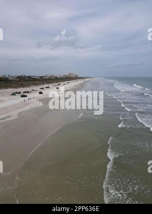 Una vista aerea di una affollata spiaggia tropicale in una giornata nuvolosa a New Smyrna Beach, Florida Foto Stock