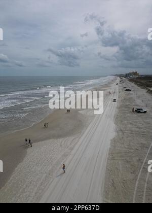 Una vista aerea di una affollata spiaggia tropicale in una giornata nuvolosa a New Smyrna Beach, Florida Foto Stock