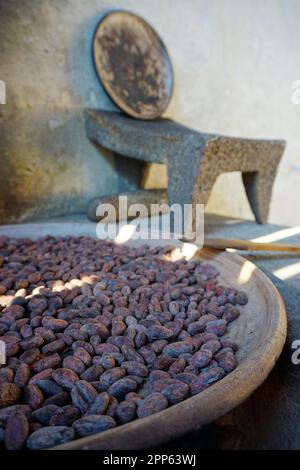 I fagioli di cacao vengono tostati su un piatto tradizionale di argilla comica in Guatemala Foto Stock