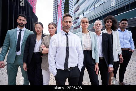 Team aziendale multiculturale guidato da boss. Posa in macchina fotografica all'esterno dell'ufficio dell'edificio. Foto Stock