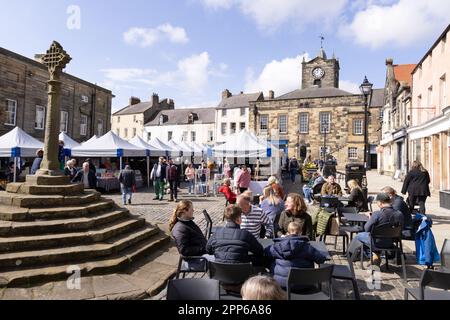 Mercato di Alnwick; gente che acquista alle bancarelle del mercato nella Piazza del mercato, sotto il sole della primavera; centro di Alnwick, Alnwick, Northumberland Regno Unito Foto Stock