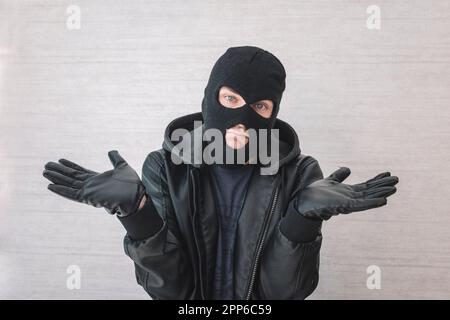 Giovane bell'uomo che indossa una maschera di scassinatore senza indizi e confuso con le braccia aperte, nessun concetto di idea. Il ladro si scusa. giustificazione dell'arresto Foto Stock