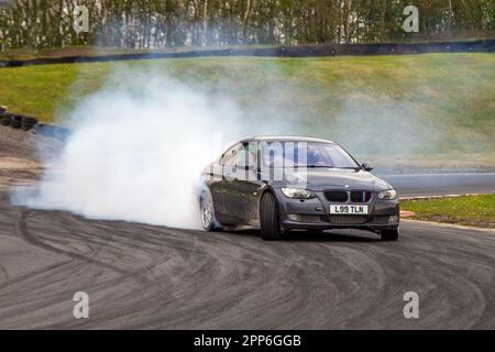 BMW 335I se Grey Car Coupe benzina da 2979 cc, gomma bruciata e pneumatici che urlano al circuito Three Sisters di Wigan, Lancashire, Regno Unito Foto Stock