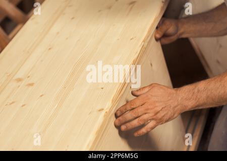 Le mani di un forte falegname tengono, guidano, trattengono, spingono e muovono il legname mentre lavora con potenti macchine da taglio nella sua officina. Le immagini trasportano stre Foto Stock