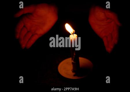 candela fiamma illumina una mano femmina in una stanza Foto Stock