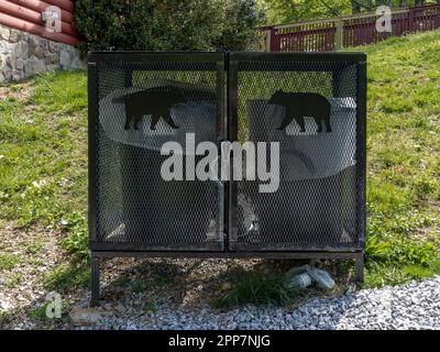 Contenitore per rifiuti a prova di orso o contenitori per rifiuti anti orso accanto a una cabina di tronchi nelle Smokey Mountains vicino a Pigeon Forge Tennessee, USA. Foto Stock