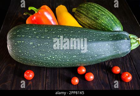 Zucchine di midollo vegetale, pepe dolce e pomodori su fondo scuro. Fotografia di squash fresco su vecchio tavolo di legno. Tema delle zucchine, biologico f Foto Stock