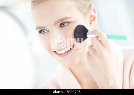 Bellezza arrossante. una donna sorridente che applica il blush con il copyspace. Foto Stock