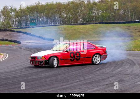 BMW Auto No.99 gomma bruciante e pneumatici che urlano a tre 3 Sisters Race Circuit a Wigan, Lancashire UK Foto Stock