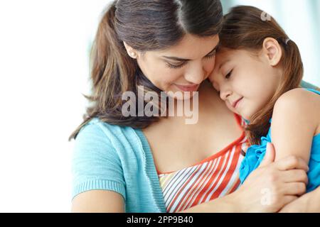 Niente come le madri amano. Una giovane madre che abbraccia affettuosamente la figlia carina. Foto Stock