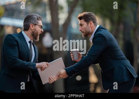 Lotta aziendale. Uomini d'affari che combattono all'aperto. Lavoratori arrabbiati in città. Uomini partner discordanti. Concorrenza aziendale. Gli uomini d'affari hanno affari Foto Stock