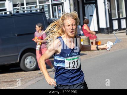 Corridore nella corsa di strada di Framlingham Flyers 10km prendendo una tazza di plastica di acqua dagli assistenti Foto Stock