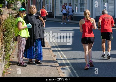 Donna vicario in un collare di cane spettatori la gara di strada Framlingham Flyers 10km Foto Stock