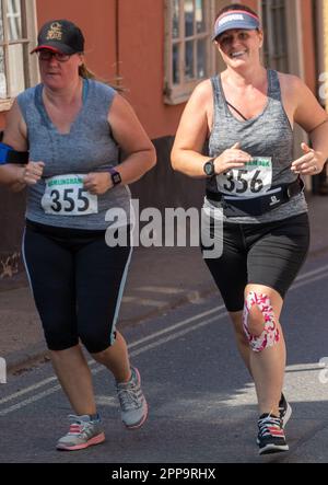 Due donne corridori che gareggiano nella corsa su strada di Framlingham Flyers 10km e indossano simili cime grigie Foto Stock