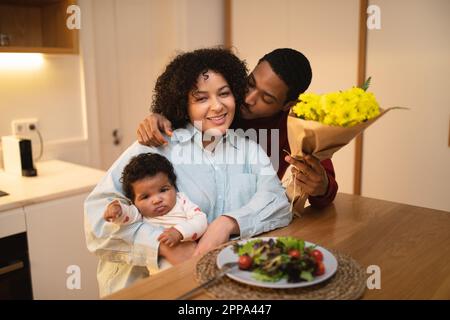 Amare il marito nero baciando la sua bella moglie che tiene il bambino ragazzo Foto Stock