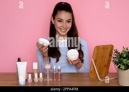 Attraente giovane donna ispanica estetista consiglia bella crema per il viso Foto Stock