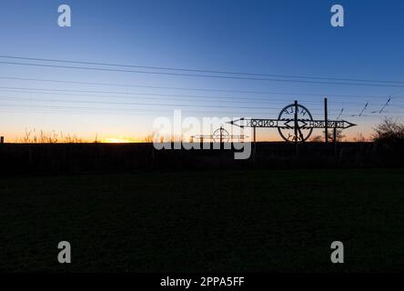 Newton on Ouse (Nord di York) da Londra a Edimburgo segnale a metà strada sulla costa orientale mainline che rende un tramonto silhouette Foto Stock