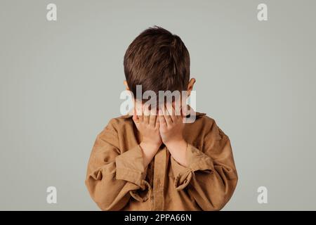 Disperato bambino piccolo triste 6 anni in pianto casual isolato su sfondo grigio, studio, primo piano Foto Stock
