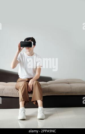 Giovane donna seduta sul divano e giocata con gli occhiali vr Foto Stock