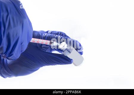 Concetto di vaccinazione. La mano del medico nei guanti blu tiene il flacone di vaccino del medicinale e la siringa. vaccino contro il coronavirus. Foto Stock