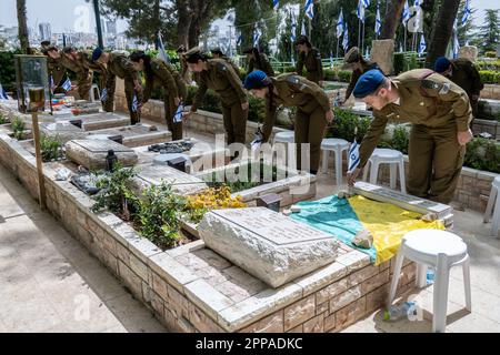 Gerusalemme, Israele. 23rd Apr, 2023. I soldati dell'IDF posano piccole bandiere israeliane con nastri neri su ciascuna delle tombe e salutano i caduti al cimitero militare del Monte Herzl prima del Memorial Day, Yom Hazikaron, per i soldati caduti di Israele e le vittime degli attacchi terroristici. Il Memorial Day sarà segnato il 24th aprile 2023. Credit: NIR Alon/Alamy Live News Foto Stock