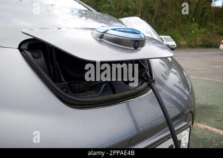 porta di ricarica anteriore per auto a balestra nissan con cavo di ricarica collegato alla contea di donegal, repubblica d'irlanda Foto Stock