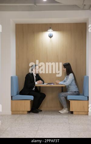 Colleghi aziendali diversi e positivi che parlano in uno stand diviso Foto Stock