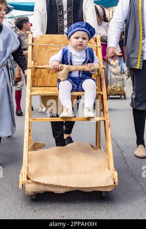 Huelva, Spagna - 18 marzo 2023: Un bambino sta facendo un giro in una carrozza rustica di legno vestita con costume d'epoca nella parata di Discove medievale Foto Stock