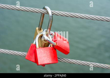 Primo piano della red lucchetti appesi ad un cavo di acciaio Foto Stock