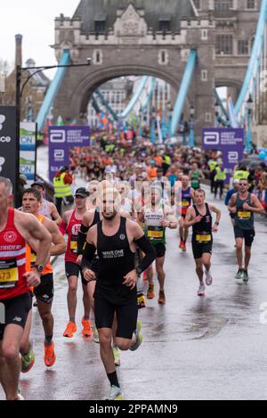 Tower Hill, Londra, Regno Unito. 23rd Apr, 2023. Circa 45.000 persone partecipano alla maratona di Londra TCS 2023, tra cui i migliori corridori d'élite del mondo e gli atleti in carrozzina. Seguono la massa di club e corridori divertenti, con molti che alzano grandi somme per beneficenza e spesso corrono in abiti eleganti e puntano ai Guinness dei primati mondiali per la classe. Corridori nella pioggia dopo aver attraversato Tower Bridge Foto Stock