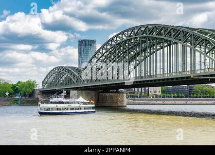 COLONIA, GERMANIA - 12 MAGGIO: Nave passeggeri che attraversa il ponte Hohenzollern a Colonia, Germania il 12 maggio 2019. Vista sulla torre Triangle Foto Stock