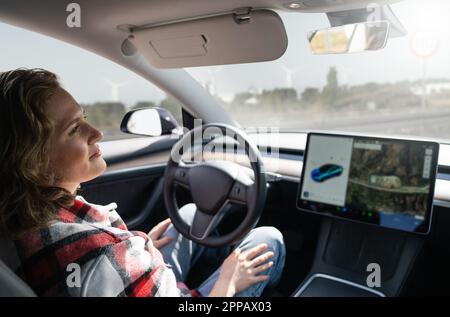Donna che riposa mentre la sua auto è guidata da un pilota automatico. Concetto di veicolo a guida autonoma. Foto Stock
