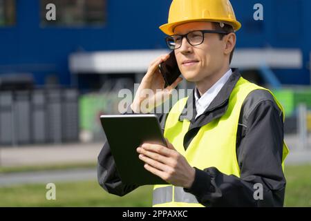 Logistico con telefono e tablet digitale sullo sfondo del centro logistico. Foto di alta qualità Foto Stock