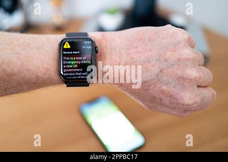 Smart Watch di una persona che visualizza un messaggio di testo di avviso del server governativo del Regno Unito. Il testo avverte la popolazione britannica di possibili emergenze e minacce. Foto Stock