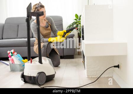 servizio di pulizia professionale. donna in uniforme e guanti spugna lava le finestre panoramiche nel cottage. lavaggio bagno turco e raschietto Foto Stock