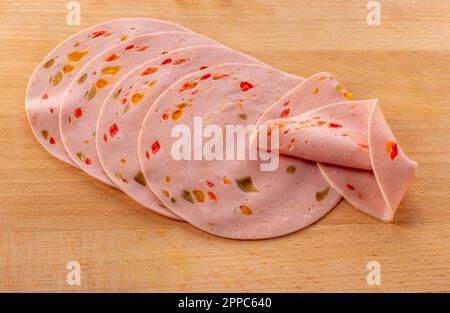 Fettine di salsiccia di paprika lyoner con peperone rosso, su tagliere di legno Foto Stock