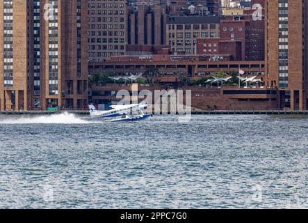 Il Tropic Oceans Airways Cessna 208B decade dalla base degli idrovolanti dello Skyports di New York sull'East River. Sfondo: Waterside Plaza Foto Stock