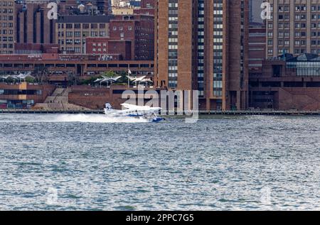 Il Tropic Oceans Airways Cessna 208B decade dalla base degli idrovolanti dello Skyports di New York sull'East River. Sfondo: Waterside Plaza Foto Stock