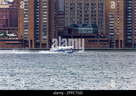 Il Tropic Oceans Airways Cessna 208B decade dalla base degli idrovolanti dello Skyports di New York sull'East River. Sfondo: Waterside Plaza Foto Stock