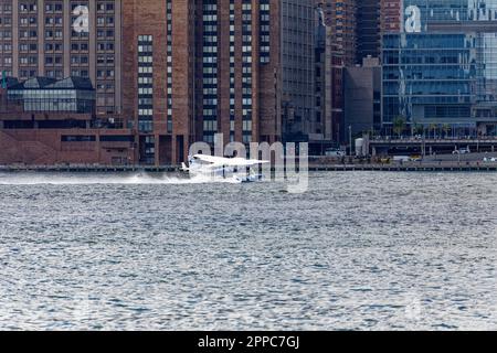 Il Tropic Oceans Airways Cessna 208B decade dalla base degli idrovolanti dello Skyports di New York sull'East River. Sfondo: Waterside Plaza Foto Stock