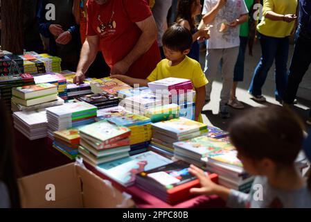 Barcellona, Spagna. 23rd Apr, 2023. I bambini si vedono comprare libri in una bancarella durante la tradizionale festa catalana del giorno di San Giorgio. In questo giorno, conosciuto come "giorno di San Giorgio" (Diada de Sant Jordi in catalano), l'amore e la letteratura vengono celebrati vendendo libri e rose rosse in tutto il paese. Dall'anno 1997 lo slogan ufficiale di questo giorno è stato 'Una rosa per un amore e un libro per sempre'. Credit: SOPA Images Limited/Alamy Live News Foto Stock