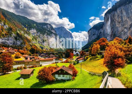 Incantevole vista autunnale della valle di Lauterbrunnen con la splendida cascata Staubbach e le Alpi svizzere al tramonto. Lauterbrunnen villaggio con autunno rosso Foto Stock