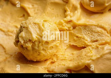 Una paletta di gelato al mango primo piano su uno sfondo di gelato al mango Foto Stock